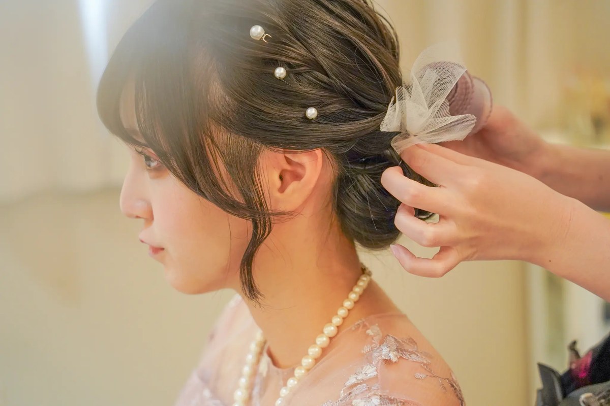 スタッフがお客様のヘアセットを丁寧に仕上げているシーン